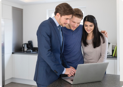 Agent and young couple in kitchen, looking at laptop together